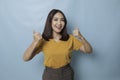 Young pretty woman smiling joyfully and looking happy, feeling carefree and positive with both thumbs up  by blue Royalty Free Stock Photo