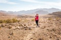 Young pretty woman standing stone desert trail, posing camera.