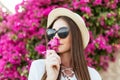Young pretty woman in sunglasses and straw hat sniff flowers on pink flowers wall in garden Royalty Free Stock Photo