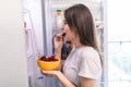 Young woman takes the cherry from the open refrigerator. Healthy food Royalty Free Stock Photo