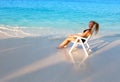 Young pretty woman tans in beach chair, it put in ocean Royalty Free Stock Photo