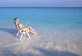 Young pretty woman tans in beach chair in sea Royalty Free Stock Photo