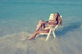 Young pretty woman tans in beach chair in sea, retro effect Royalty Free Stock Photo