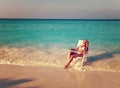 Young pretty woman tans in beach chair.Sea tropical landscape in a sunny day,with a retro effect Royalty Free Stock Photo