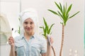 A young pretty woman with a towel on her head in a bright bathroom with a toothbrush and paste in her hands against the background