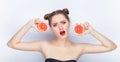 Young pretty woman trendy makeup bright red lips bun hairstyle bare shoulders act the ape with grapefruits white studio background