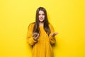 Young pretty woman typing on the phone or serf in internet wearing in yellow sweater isolated on yellow background