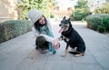 Young and pretty woman in a white cap hugs and kisses her dog with one eye of each color. Love between owner and dog Royalty Free Stock Photo