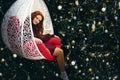 Young pretty woman in a wicker rocking chair near the New Year tree