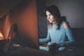 Young pretty woman working on modern studio office at night. Girl using contemporary desktop computer, blurred