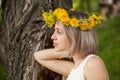 Young pretty woman in yellow flowers wreath outdoor. Healthy girl in flowers garden