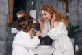 Young pretty woman with blonde hair teaches her little curly son to brush his teeth using a toothbrush and toothpaste. Royalty Free Stock Photo