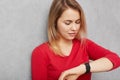 Young pretty young woman checks time on wrist watch, being in hurry or late for meeting, waits for someone, tired of waiting, isol Royalty Free Stock Photo