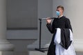 Young priest with protective face mask going to the church to celebrate mass