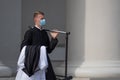 Young priest with protective face mask going to the church to celebrate mass