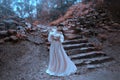 Young princess with very long hair posing against the background of an old stone staircase. The girl has a crystal crown Royalty Free Stock Photo