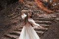 Young princess with very long hair posing against the background of an old stone staircase. The girl has a crystal crown