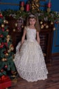 Young princess in a white dress with a tiara on her head at the Christmas tree Royalty Free Stock Photo