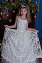 Young princess in a white dress with a tiara on her head at the Christmas tree Royalty Free Stock Photo