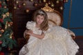 Young princess in a white dress with a tiara on her head at the Christmas tree Royalty Free Stock Photo