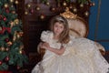 Young princess in a white dress with a tiara on her head at the Christmas tree Royalty Free Stock Photo