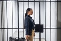 A young prison guard poses in front of prison bars in uniform. In a maximum security prison