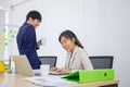 A young, professional young Asian businesswoman is sitting at her desk and sipping afternoon coffee with a male office worker Royalty Free Stock Photo