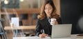 Young professional asian businesswoman working on her project while typing on laptop computer in modern office