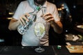 Young professional bartender pours alcohol from a bottle into a glass at a nightclub or bar. Cooking delicious original cocktail Royalty Free Stock Photo