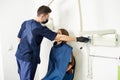 Young professional in a blue uniform is taking care of a female patient in a white dental office