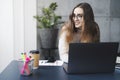 Young professional doing creative project on laptop. Girl sitting by computer at office desk. Digital tools and solutions for