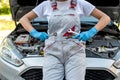 Young professional female mechanic inspects under the hood of a car.