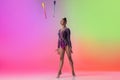 One female rhythmic gymnast exercising with clubs isolated on colored gradient neon background.