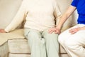 Young caregiver helping senior woman with knee pains at home. Caring nurse assisting her patient. Royalty Free Stock Photo