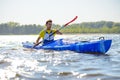 Young Professional Kayaker Paddling Kayak on River under Bright Morning Sun. Sport and Active Lifestyle Concept