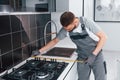 Young professional plumber in grey uniform measuring table by using meter on the kitchen Royalty Free Stock Photo