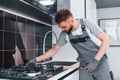 Young professional plumber in grey uniform measuring table by using meter on the kitchen Royalty Free Stock Photo