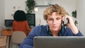 Young Startup Team Member On Phone At Desk With Laptop In Modern Office Setting Royalty Free Stock Photo