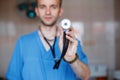Young professional surgeon doctor in special medical clothes is holding a phonendoscope in his hand. Doctor takes care of the