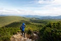 Young professional traveller man with dslr camera shooting outdoor fantastic mountain landscape. Hiker stands on a rock