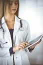 Young professional woman-doctor is using a tablet computer, while standing in a clinic. Portrait of beautiful female Royalty Free Stock Photo