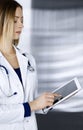 Young professional woman-doctor is using a tablet computer, while standing in a clinic. Portrait of beautiful female Royalty Free Stock Photo