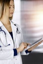 Young professional woman-doctor is using a tablet computer, while standing in a clinic. Portrait of beautiful female Royalty Free Stock Photo