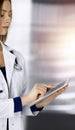 Young professional woman-doctor is using a tablet computer, while standing in a clinic. Portrait of beautiful female Royalty Free Stock Photo