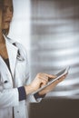 Young professional woman-doctor is using a tablet computer, while standing in a clinic. Portrait of beautiful female Royalty Free Stock Photo