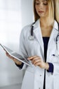 Young professional woman-doctor is using a tablet computer, while standing in a clinic. Portrait of beautiful female Royalty Free Stock Photo