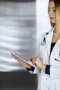 Young professional woman-doctor is using a tablet computer, while standing in a clinic. Portrait of beautiful female Royalty Free Stock Photo