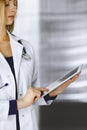 Young professional woman-doctor is using a tablet computer, while standing in a clinic. Portrait of beautiful female Royalty Free Stock Photo