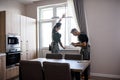 Young professional worker in uniform using tape measure, measuring window for installing blinds, while his aged