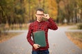 Young professor in glasses holding folders in autumn park